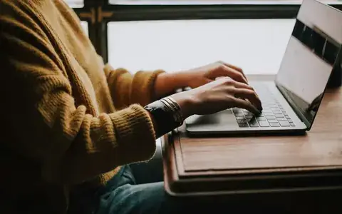 Laptop on a desk while someone types a brief